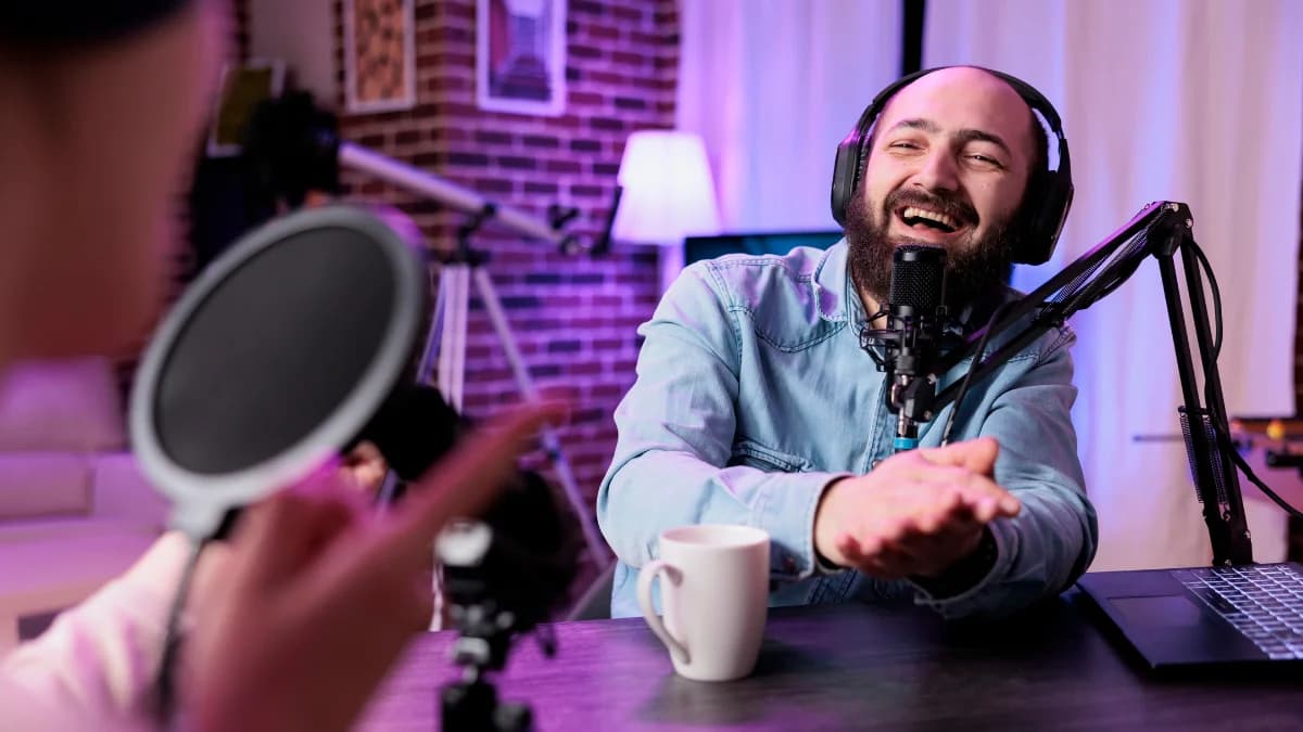 Two people recording a podcast, one speaking into a microphone while wearing headphones